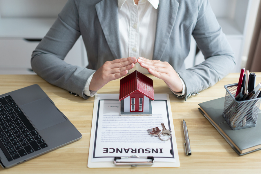dwelling insurance concept - insurance agent hands protecting house model